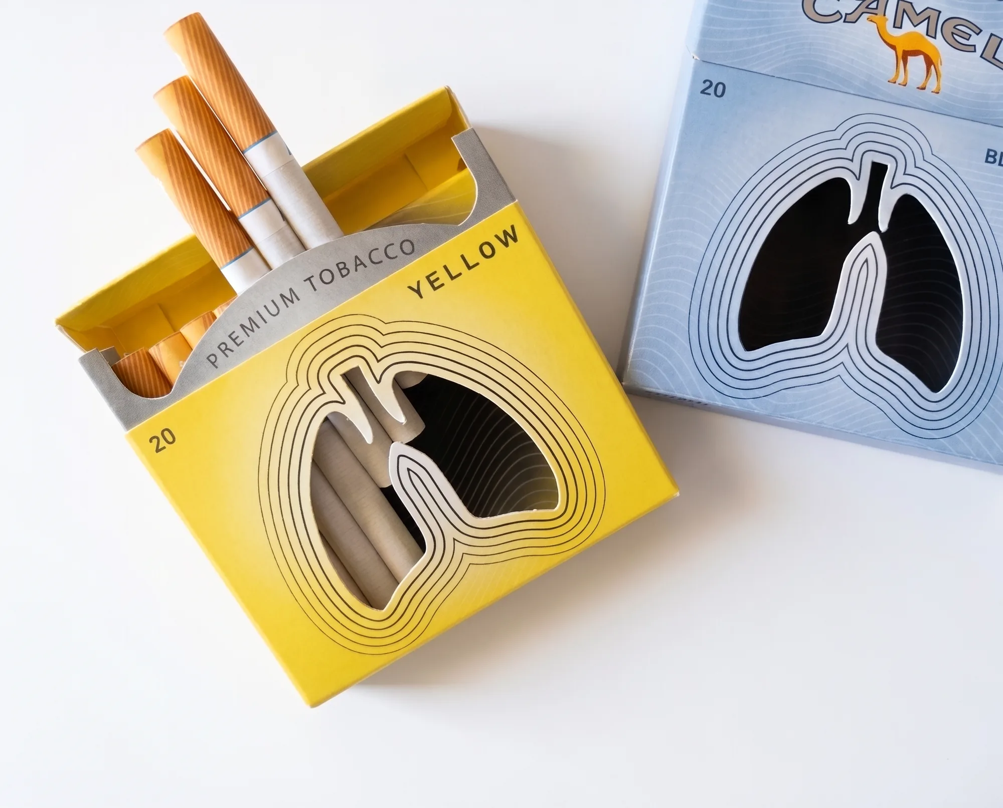 The Yellow pack open with three cigarettes offered, next to a Blue pack with the lungs already black.